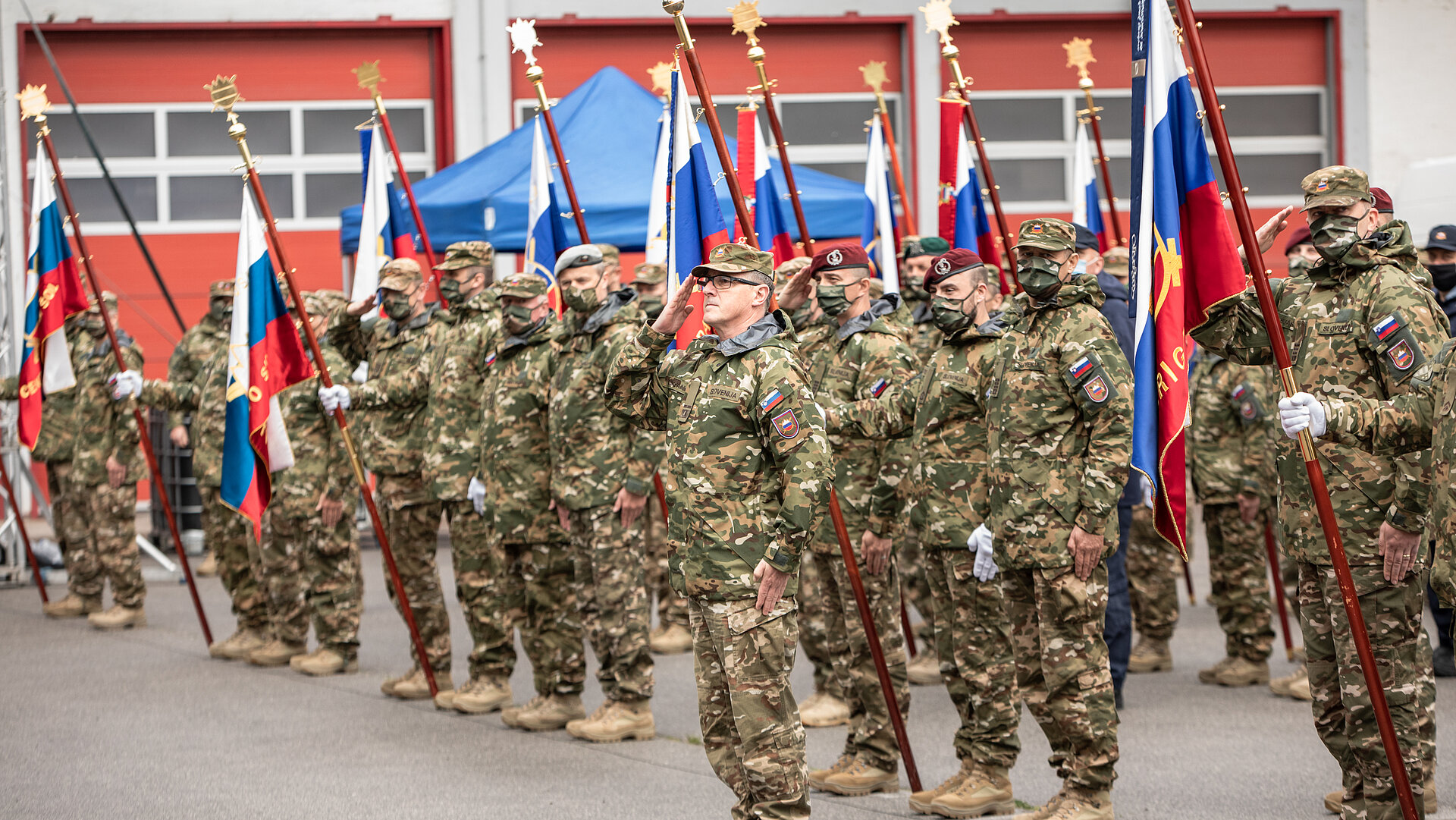 Pripadniki slovenske vojske v postroju pozdravljajo z roko